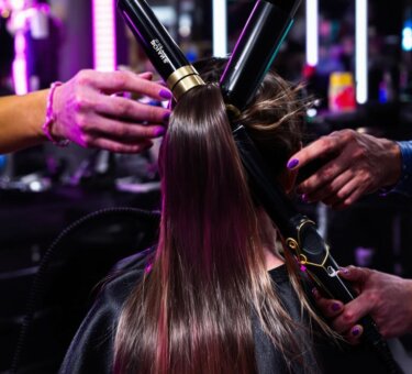 Hairstylist using vibrant professional tools in a modern salon setting.